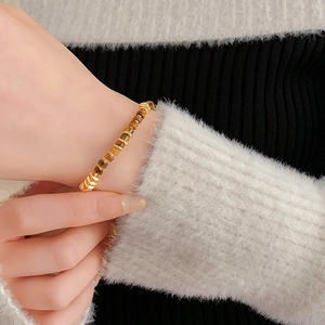 Close-up of tiger eye bead bracelet with gold metal accents on model in knit sweater