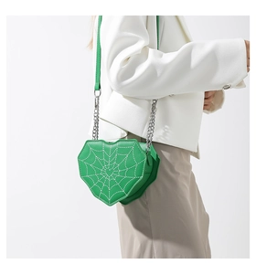 Detalle del bolso bandolera de corazón verde con costuras de telaraña y correa de cadena