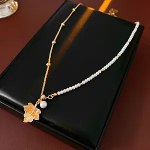 Gold plated maple leaf pendant necklace with pearls on a black leather jewelry display