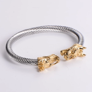 Close-up of dual-tone dragon head terminals on a twisted stainless steel cable bracelet