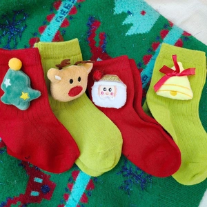 Christmas themed kids socks with 3D reindeer and Santa plush toys on festive knit background