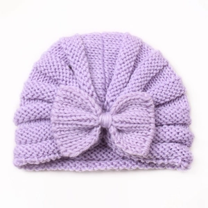 Close-up of purple knit baby hat featuring detailed stitch texture and a large bow