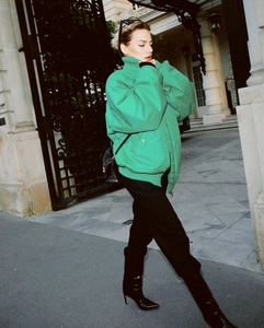Detail of green oversized bomber jacket with ribbed cuffs and zip closure on the street