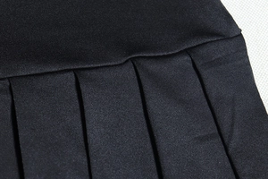 Detail view of precise pleats and stitching on a black high-waisted pleated skirt