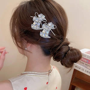 Detail of sparkling rhinestone boot hair clips in silver finish with bow accents