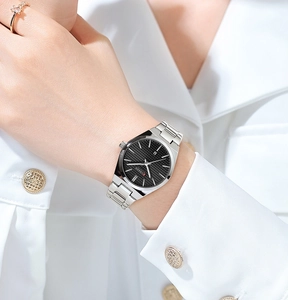 Detail of silver stainless steel watch with black dial worn on wrist with a white shirt