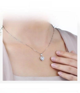 Dettaglio di un ciondolo a cuore con zircone su catena box in argento indossato da modella