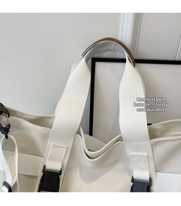 Close-up of white canvas handbag with comfortable wide handle and sturdy side buckle