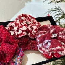 Detail of red houndstooth and tweed scrunchies with elegant textures on a tray
