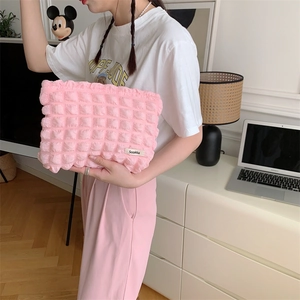 Pink bubble textured canvas cosmetic bag held by a model in a cozy home setting