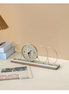 Detail view of a golden metal GOOD letter clock with wood grain face and solid base