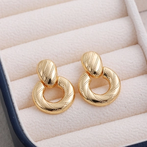 Close-up of 18K gold hollow spherical earrings with spiral texture on velvet background