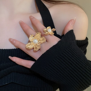 Detail view of irregular hammered gold flower rings with pearls worn on fingers