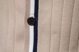 Vista macro del cardigan in maglia kaki con striscia blu e bottone nero tondo