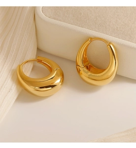 Macro shot of thick gold teardrop hoop earrings with high-polish mirror finish surface