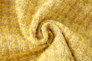 Macro detail of yellow tweed fabric showing intricate woven texture and metallic fibers