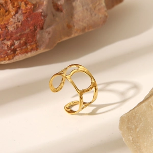 Détail d'une bague dorée ajustable avec texture irrégulière évidée sur fond de pierre