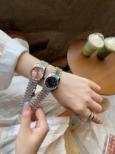 Detailed view of silver steel women's watches with pink and black dials on wrist