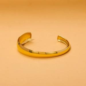 Macro view of polished 18K gold plated stainless steel C-shaped cuff with bamboo texture