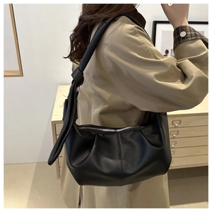 Detail of black lychee grain leather hobo bag with knotted strap on model's shoulder