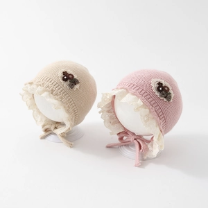 Close-up of knit baby hats featuring delicate white lace trim and floral ribbon accents