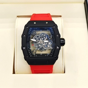 Detail of tonneau-shaped skeleton watch with red silicone strap in a beige display box