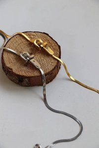 Dettaglio di collane a serpente in oro e argento con pendenti a fibbia moderni