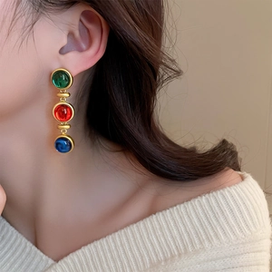 Détail de boucles d'oreilles rétro avec gemmes vertes, rouges et bleues et cadre doré