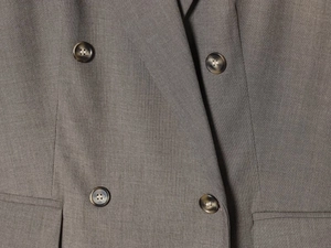 Macro shot of grey double-breasted suit fabric texture and tortoise buttons
