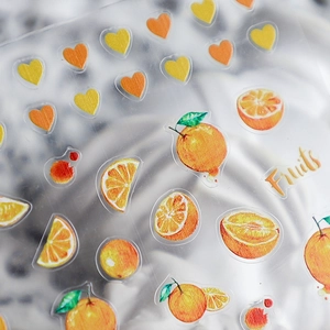 Watercolor orange fruit nail art stickers with heart motifs on grey fabric background