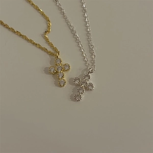 Detail of cross pendant necklaces in gold and silver finish with sparkling stones
