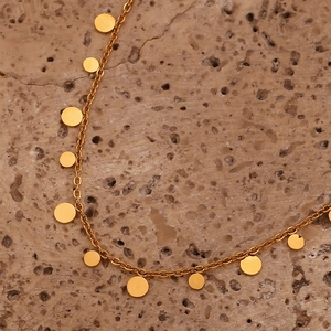 Macro view of minimalist 18K gold plated stainless steel necklace on natural stone