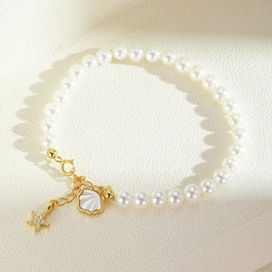 Elegant S925 silver pearl bracelet with starfish and shell charms on a beige surface