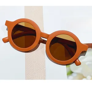Detail view of round orange matte frame sunglasses for kids on a magazine background