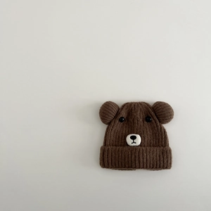 Texture détaillée d'un bonnet d'hiver marron en tricot avec oreilles d'ours et broderie