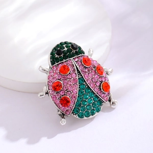 Detailed view of ladybug brooch with colorful crystals on a white ceramic tray