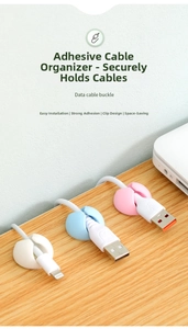 Close-up of silicone cable clips in white and pastel colors on a wooden desktop