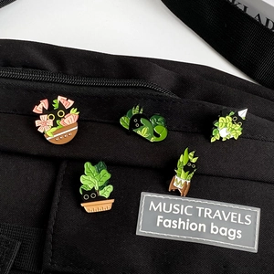 Detail of five cute black cat enamel pins with plants on a black canvas bag