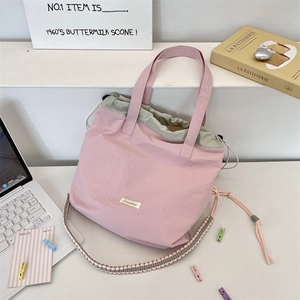 Flat lay of pink canvas tote bag with woven shoulder strap and drawstring closure