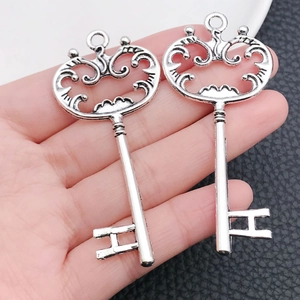 Gros plan de deux pendentifs clés vintage en argent avec motifs évidés complexes