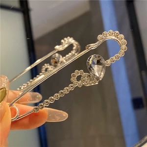 Macro shot of silver brooch pin with water-drop crystal and small rhinestones
