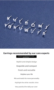 Macro shot of S999 silver alphabet stud earrings arranged on a deep blue textured surface