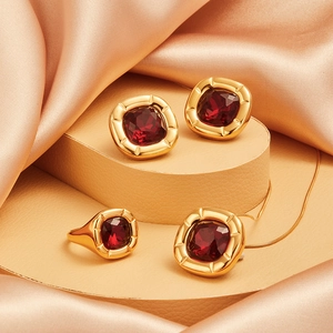 Detail of luxury 18K gold plated square zircon jewelry set on silk textured background