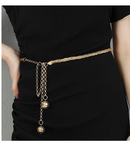 Detail of golden metal chain belt with woven texture and hollow spherical tassel pendants