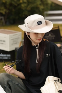 Détail du chapeau de soleil beige avec évents respirants et cordon coupe-vent réglable