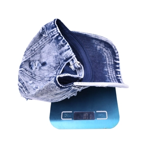 Retro washed denim baseball cap with distressed holes and metal buckle shown on scale