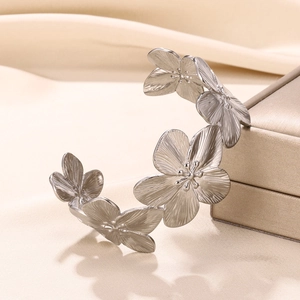 Detailed close-up of floral pattern on a wide stainless steel open cuff bracelet