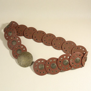 Detail of vintage brown circular leather belt with metal rings and hammered buckle texture