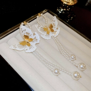 Detail of elegant butterfly tassel earrings with white lace wings and faux pearls
