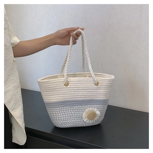 Detail of color-block straw tote bag with daisy ornament and woven rope handles